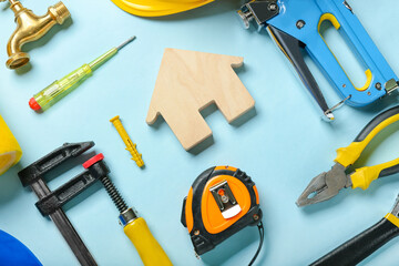 Composition with figure of house and construction tools on color background