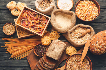 Different cereals, raw pasta and bread on dark wooden background