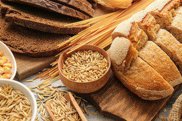 Different cereals, raw pasta and bread on wooden background, closeup