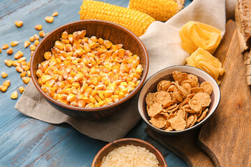 Different cereals and raw pasta on color wooden background, closeup