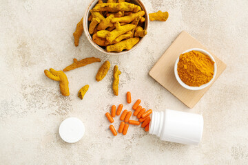 Turmeric pills, powder and roots on light background