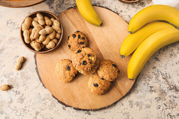 Board with tasty cookies, bananas and peanuts on grunge background