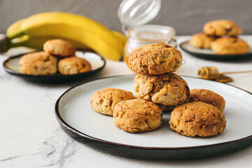 Plate with tasty banana cookies on light background