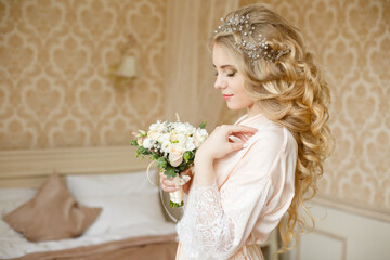 Pretty young girl. Blonde woman with luxurious long curly hair. Boudoir morning of the bride. Taking wedding bouquet in her hands