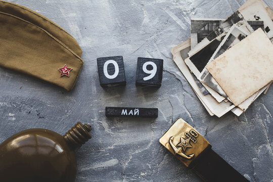 Flask, cap, soldier belt with a five-pointed star with a hammer and sickle. old photographs of the war years and a wooden calendar with the date May 09.  Victory Day .Russian text on May 9