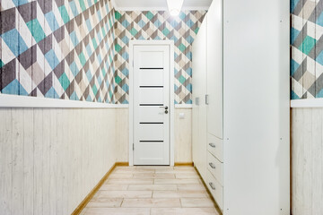 Apartment corridor with white wooden closet and geometric pattern on walls