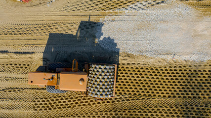 Aerial view on road roller with spikes is working at construction site, compacting base for asphalt...