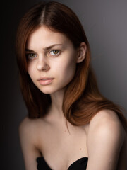 Fototapeta premium Red-haired woman with bared shoulders portrait close-up dark background model