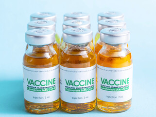 Row of bottles with coronavirus vaccine on a blue background. Side effect of the vaccine, macro, clinical