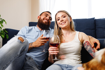 Couple sitting on sofa at home and drinking wine