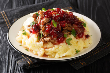 Portion of homemade venison with mashed potatoes and lingonberry sauce close-up in a plate on the table. horizontal