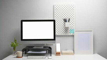 Front view of computer with blank screen, smart phone and office supplies at contemporary workplace.