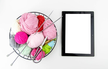 Online knitting training. View from above on the tablet and yarn for knitting, spokes, scissors.
