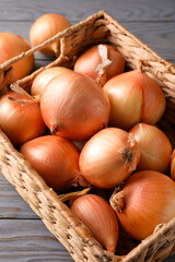 Basket with fresh onion on wooden background
