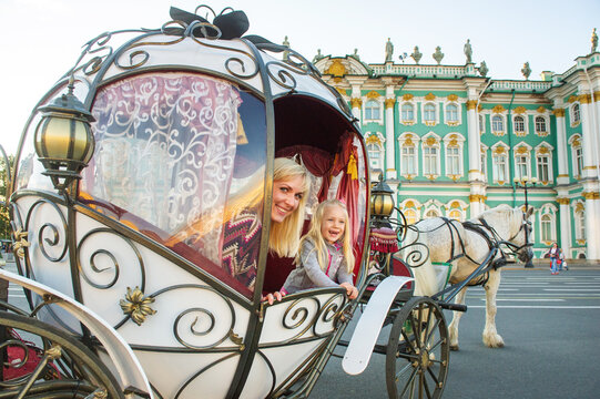 A girl with a child in an old carriage on Palace Square in St. Petersburg