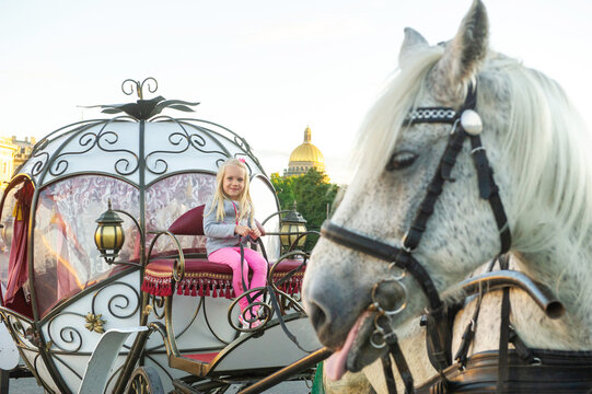 a child sits in the driver's seat in an old carriage on Palace Square in St. Petersburg