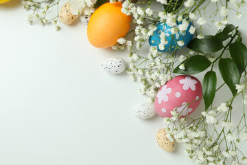 Easter eggs and beautiful flowers on white background, space for text