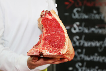 Metzger hält ein Dry Aged T-Bone Steak in der Hand