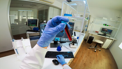 POV of scientist analysing blood sample from test tube typing on computer. Viorolog researcher in professional lab working to discover medical treatment, team of doctors analysing vaccine evolution