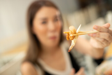 Woman eats Chili Fresh Pawn and hanging on chopstick