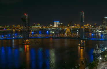main street bridge (John T. Alsop Jr.) in Jacksonville, Florida bathed in blue neon lights after dark. St. Johns river passes underneath.