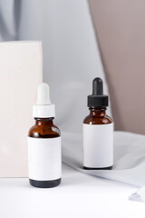 Pipette with drop of cosmetic oil above brown bottle with box