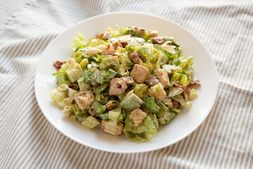 Homemade Bacon Avocado Caesar Salad with Cheese and Croutons, side view.