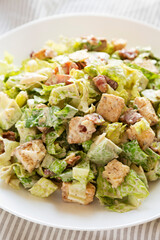Homemade Bacon Avocado Caesar Salad with Cheese and Croutons, side view. Close-up.