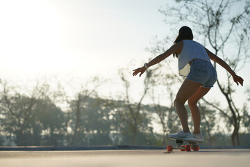 Fototapeta na wymiar Asian women surf skate or skates board outdoors on beautiful summer day. Happy young women play surf skate at park on morning time.