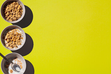 Cornflakes with milk in gray bowl on yellow background, copy space.