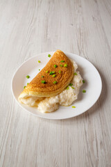 Homemade Fluffy Omelet on a white plate on a white wooden background, side view.