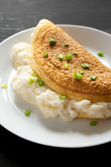 Homemade Fluffy Omelet on a white plate on a black background, low angle view. Close-up.