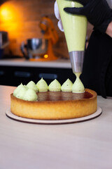 pastry chef squeezes whipped green cream onto pistachio shortbread.