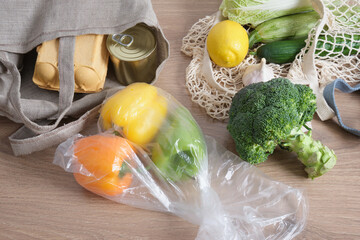 peppers in a plastic bag on a wooden kitchen table, and groceries in eco mesh bags, say no to plastic, zero waste lifestyle concept