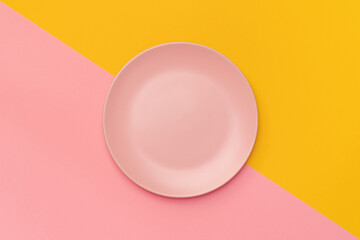 Pink plate on a background divided diagonally into pink and yellow. Minimalism. Minimal cooking...