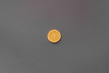 Slice of a lemon on a gray background. The lemon in the center of the frame. Minimalism