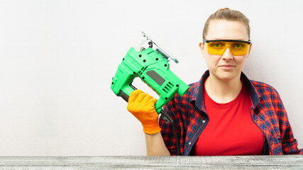 Beautiful girl with an electric jigsaw on a white