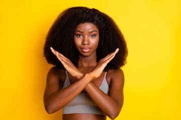 Photo of serious strict lady crossed palms look camera wear grey singlet isolated yellow color background