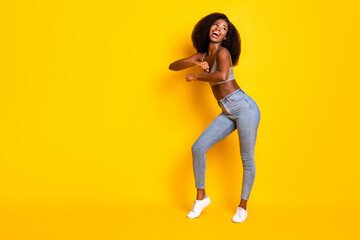 Fototapeta na wymiar Photo of lady festal dance look empty space wear grey cropped top jeans shoes isolated yellow color background
