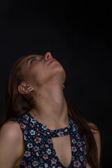 Obraz premium brown-haired woman with long hair, in a blue dress with flowers, on a black background