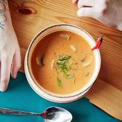mushroom orange soup in a plate with a spoon on a wooden table top view