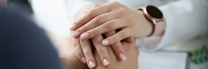 Fototapeta premium Doctor holding hands of patient in office closeup