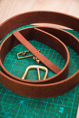 Leather pieces for belts are on the table together with gold plaques