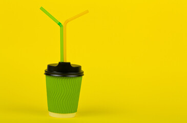 Green paper cup on a yellow background.