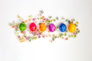 Fototapeta na wymiar Row of Colorful painted Easter Eggs isolated on white background surrounded with flowers top view background, Happy Easter concept modern design