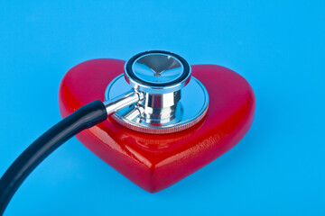 Stethoscope and red heart on a blue background close-up.