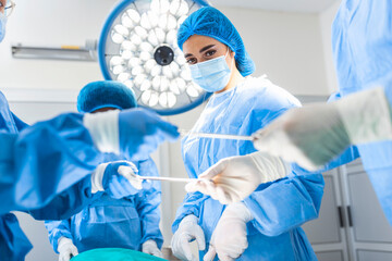 Shot in the Operating Room, Assistant Hands out Instruments to Surgeons During Operation. Surgeons...