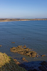 Some of the Red Sandstone rocks exposed by the low tide at Lunan Bay with the waves of the receding tide gently lapping against them,