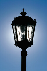 Dark silhouette of a street lamp lit from behind by the sun