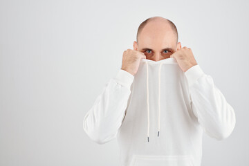 Portrait of handsome mature man covering face with hoodie and looking at camera